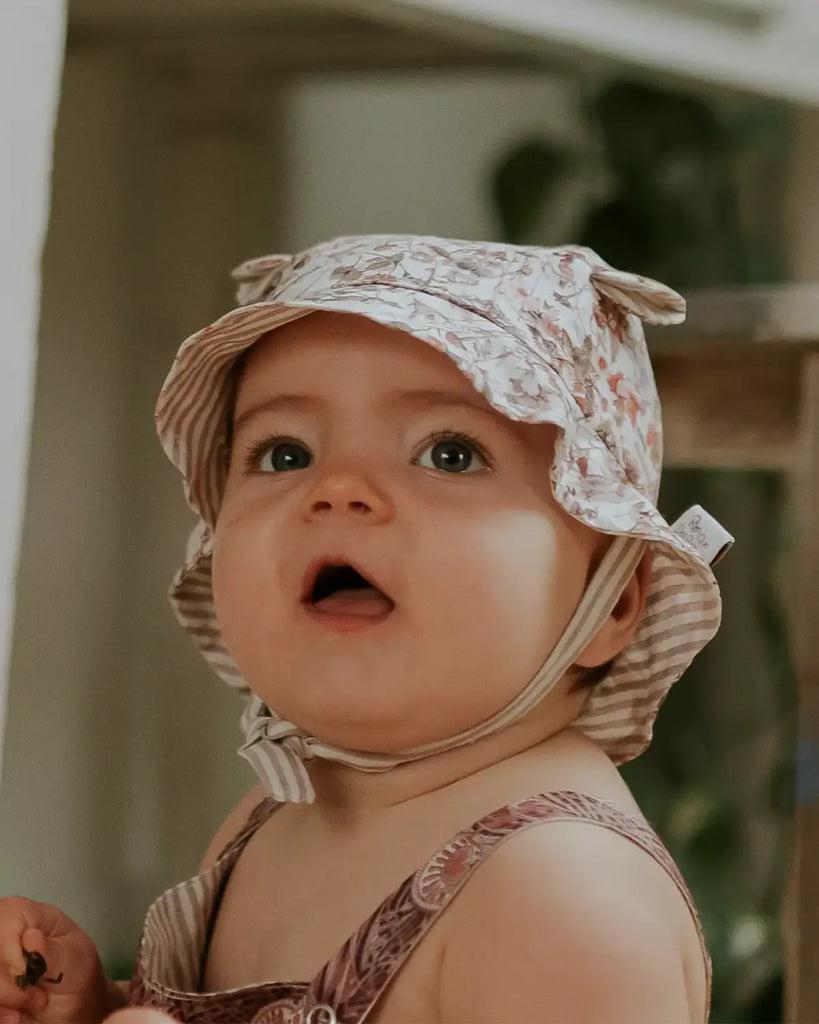 Image d'un bébé portant le chapeau pour bébé couleur crème à motif fleuri de la marque Bobine Paris.