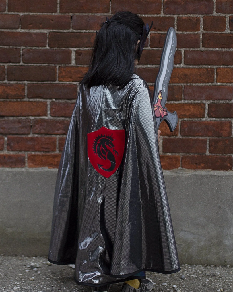 Enfant portant une cape métallique avec un écusson rouge au dos, et une épée grise