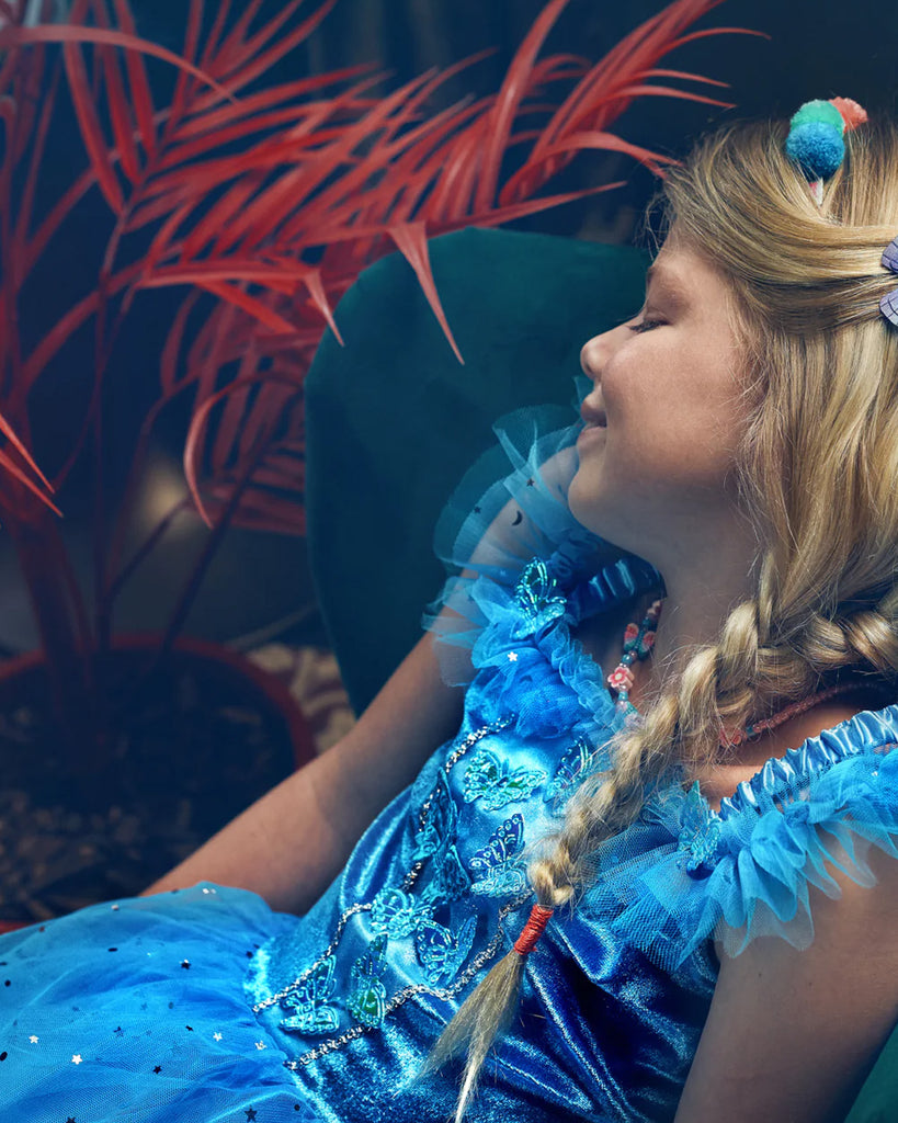 Petite fille portant une robe de princesse bleue ornée de broderies papillons et d'étoiles