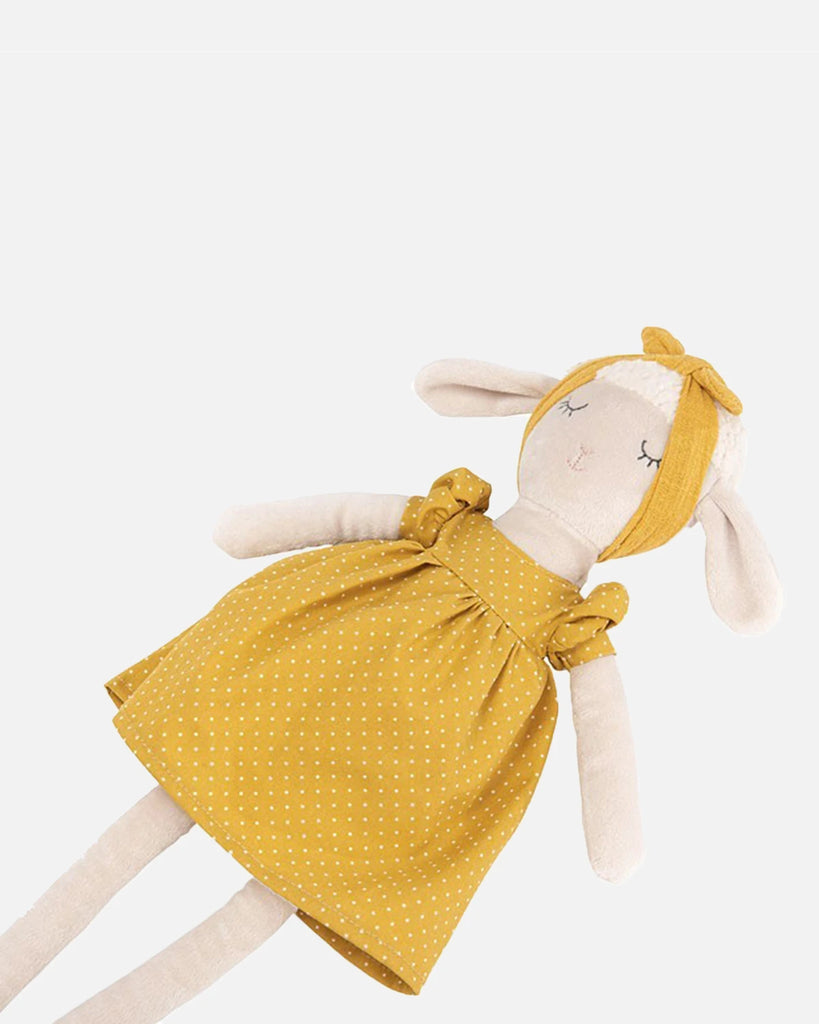 Léger zoom de la peluche mouton portant une robe jaune moutarde à pois de la marque Bobine Paris vue de côté.