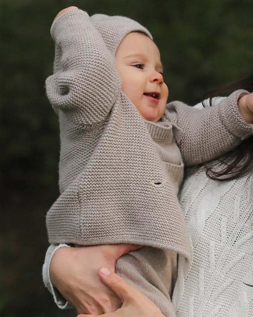 Image d'un enfant portant la veste bébé à capuche en maille beige clair de la marque Bobine Paris.