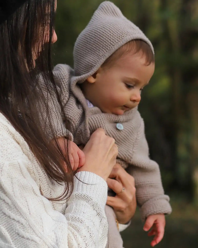 Veste bébé à capuche en maille beige clair de la marque Bobine Paris portée par un enfant.