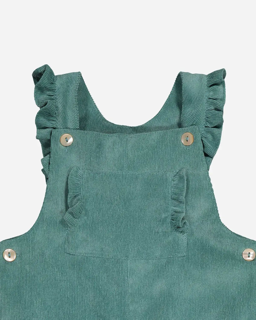Zoom de la salopette pour bébé fille vert amande avec bretelles et poches à volants de la marque Bobine Paris.