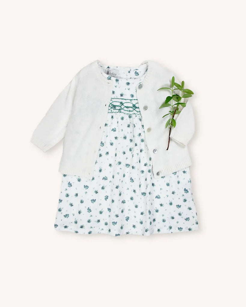 Look pour bébé fille composé d'une robe blanche à fleurs bleues et d'un cardigan écru de la marque Bobine Paris.