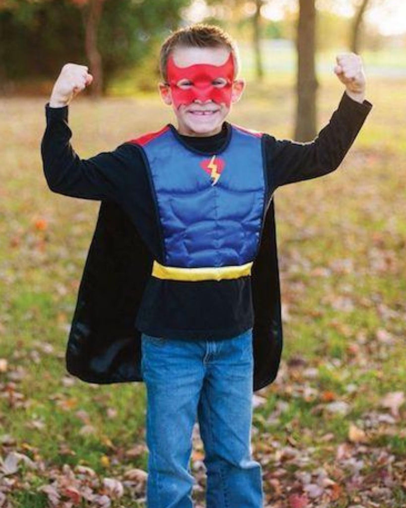 Petit garçon portant un masque rouge de déguisement et une cape avec écusson superman sur le devant