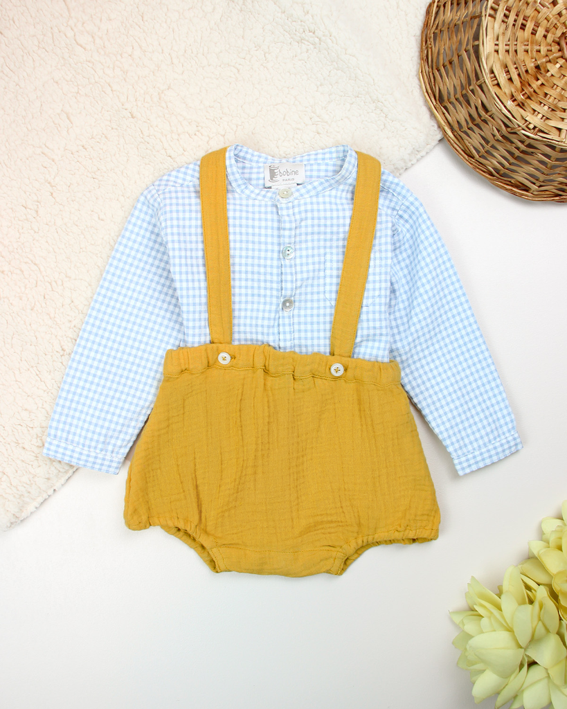Bloomer pour bébé à bretelles en gaze de coton couleur curry associé avec une chemise à carreaux bleus de la marque Bobine Paris.
