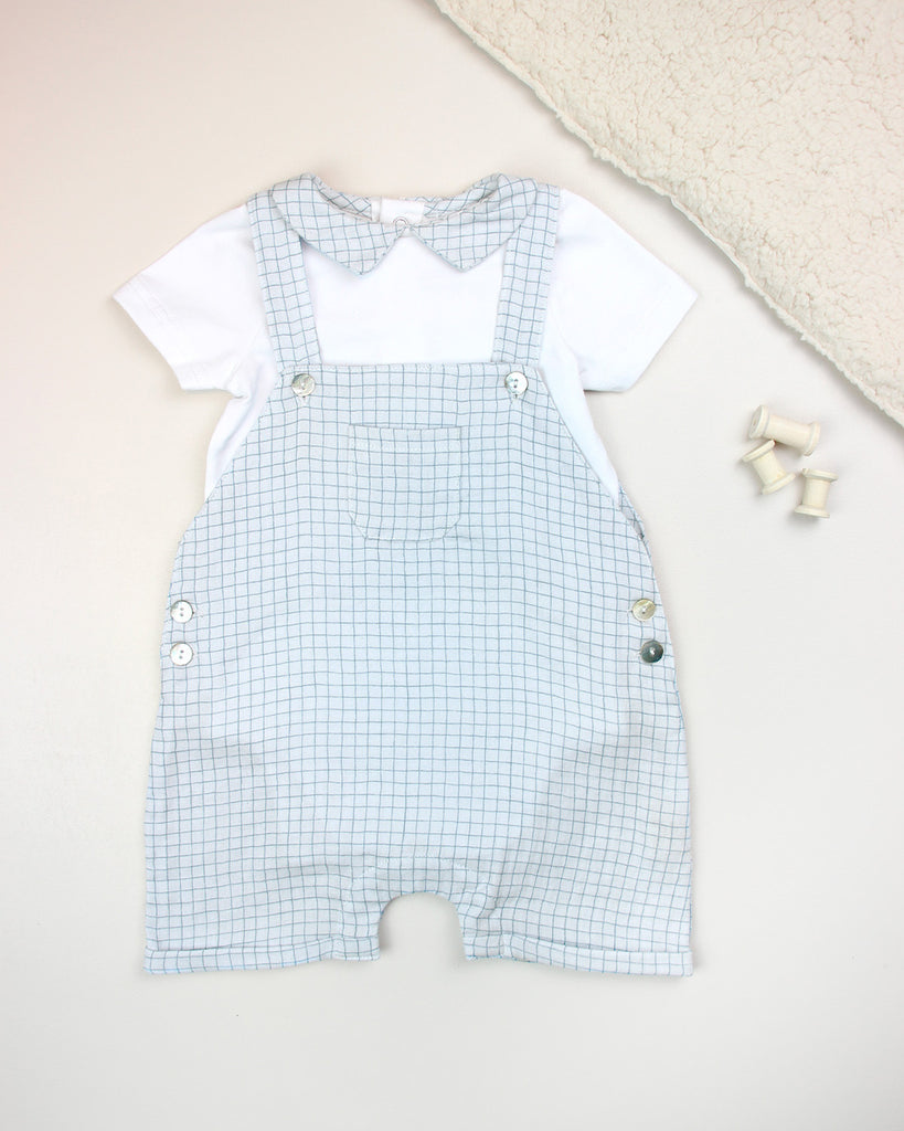 Look constitué d'une salopette pour bébé garçon à motif quadrillé bleu et d'un t-shirt blanc avec col point assorti de la marque Bobine Paris.