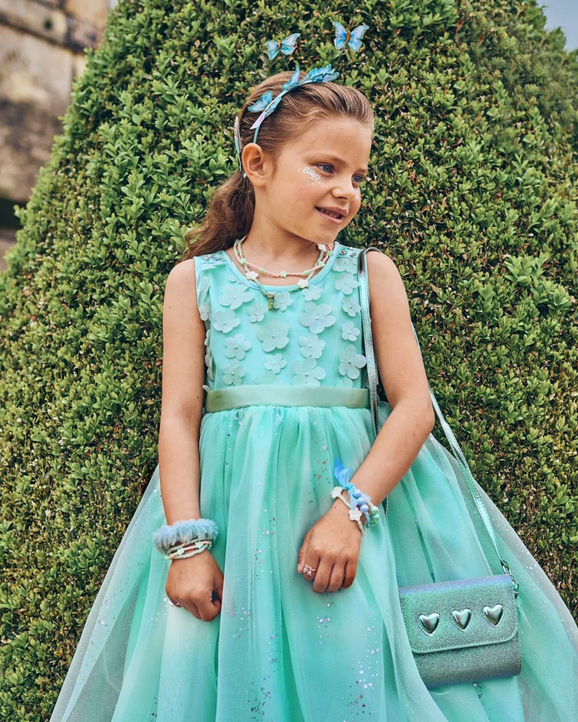 Petite fille portant une robe en tulle et sequins bleu avec des détails floraux sur le haut de la robe