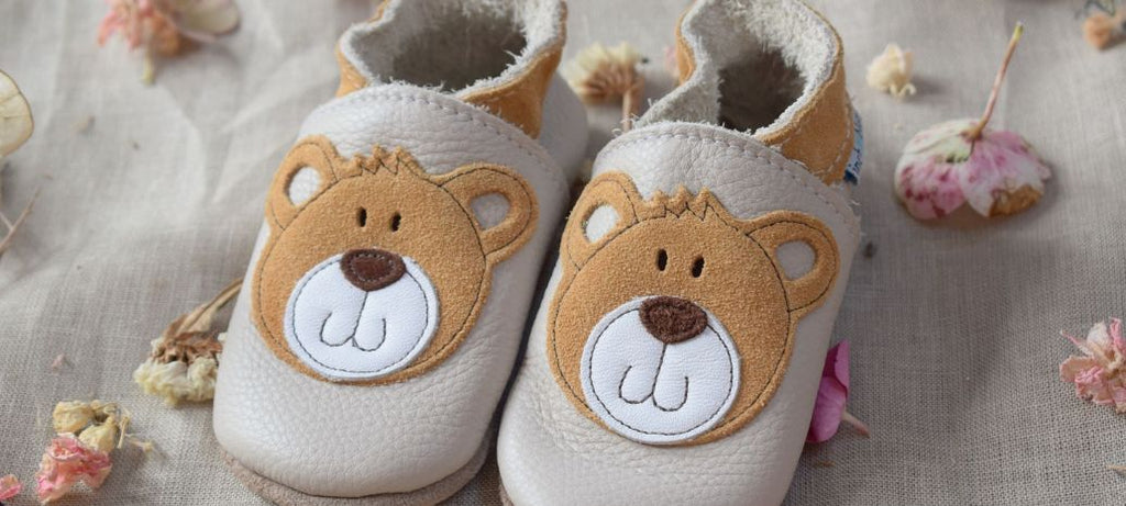 Image de chaussons pour bébé en cuir et daim beige avec un empiècement représentant un ourson.