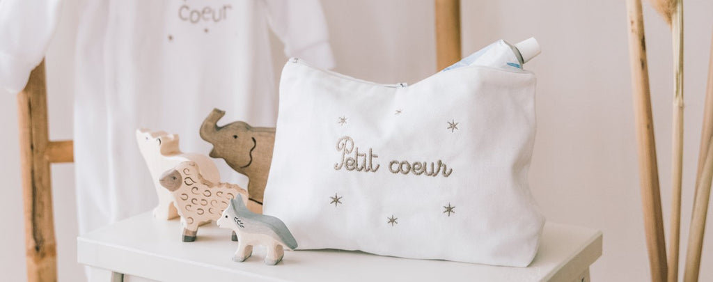 Image d'un coffret de naissance pour bébé fille comprenant un bavoir, un pyjama et un lange blanc et rose. Les articles sont brodés avec le message 'La princesse de sa maman'.