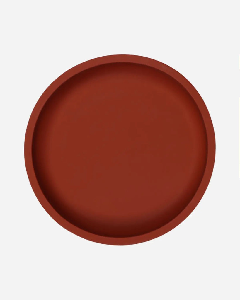 Vue de coté de l'assiette en silicone ronde de couleur rouge rouille pour bébé et enfant