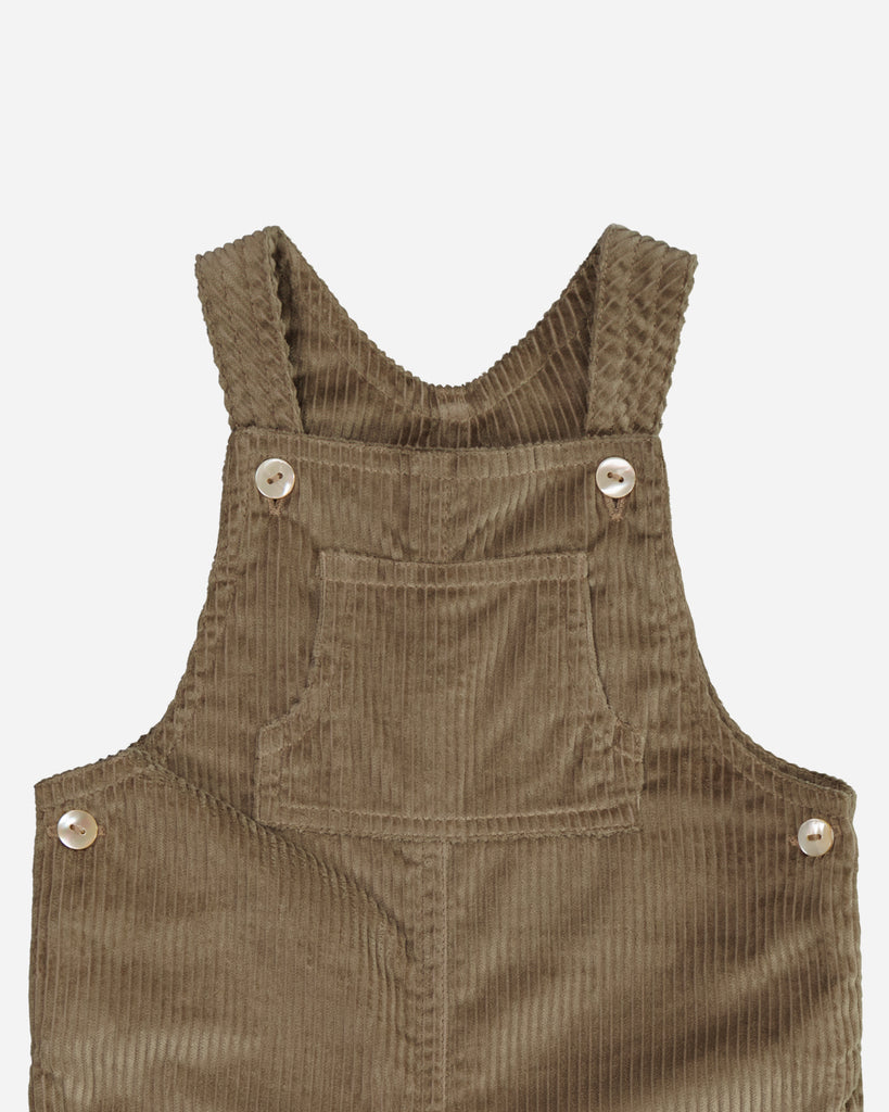 Zoom sur le col et manches bretelles de la salopette taupe en velours.