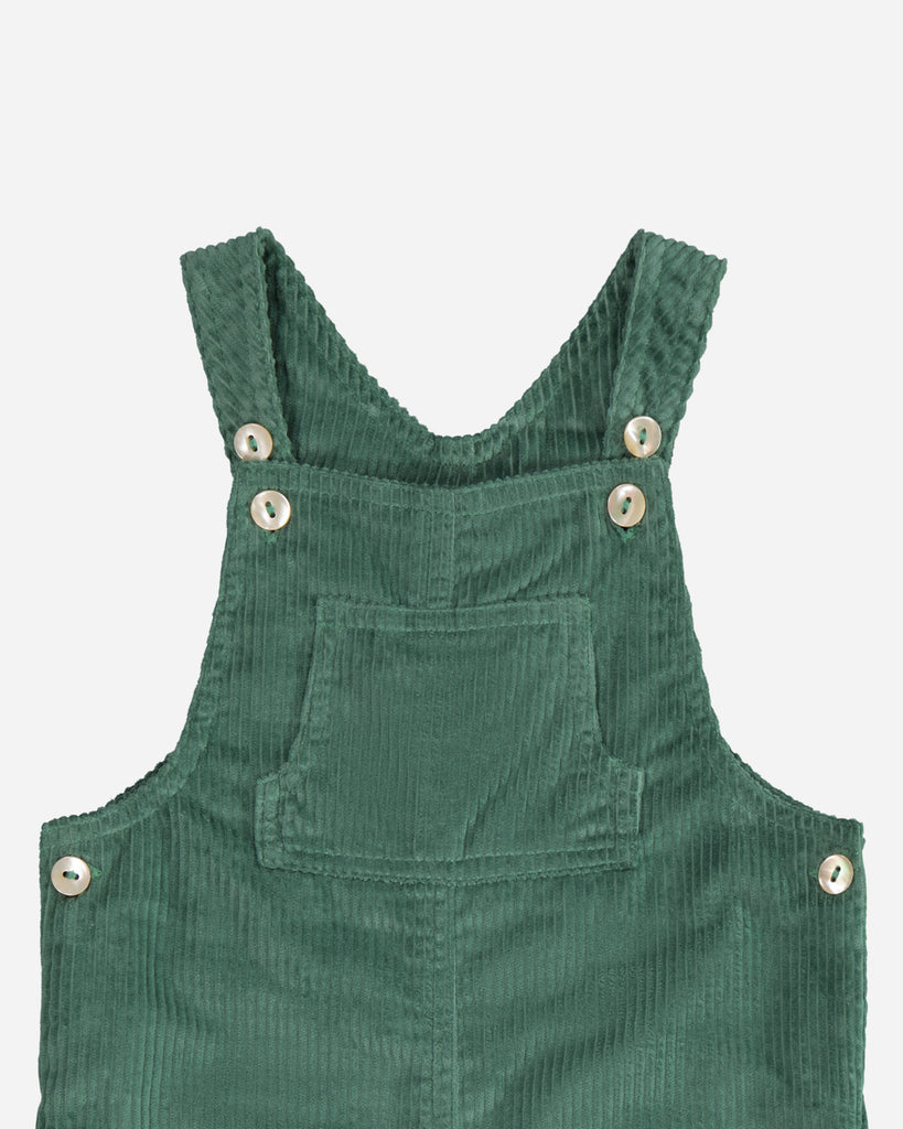 Zoom sur le col et manches bretelles de la salopette vert en velours.