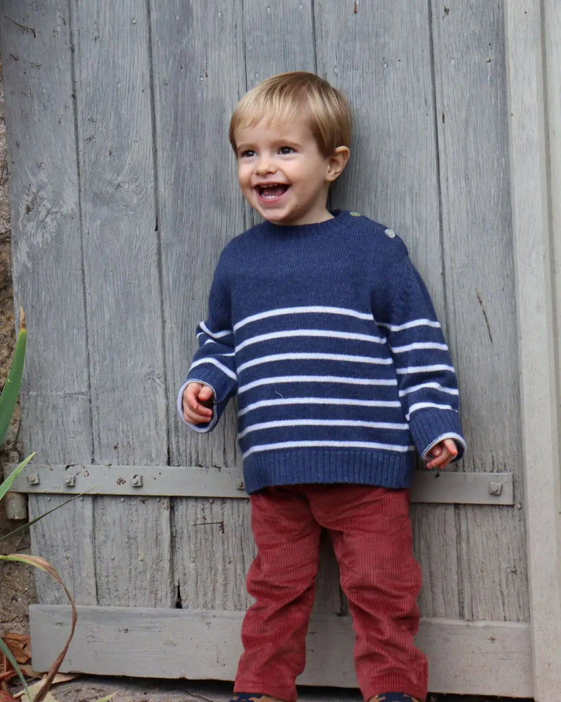 Petit garçon qui joue en portant le pull bébé bleu à rayures blanches en laine et cachemire de la marque Bobine Paris