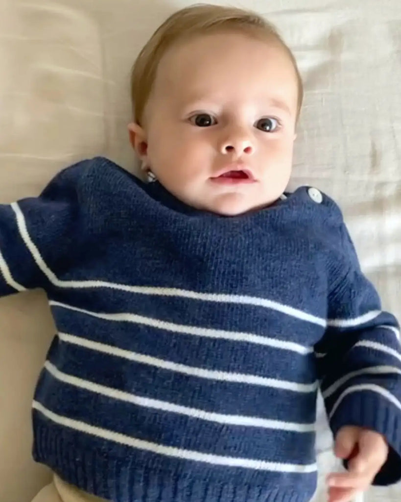 Petit garçon portant le pull bébé bleu à rayures blanches en laine et cachemire de la marque Bobine Paris.