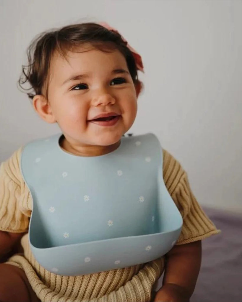 Photo d'un bébé portant le bavoir en silicone à imprimé marguerites de la marque Bobine Paris.
