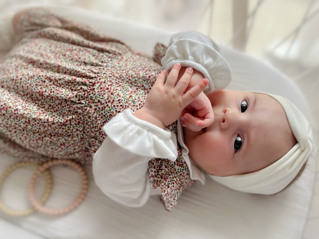 Photo d'un bébé fille qui porte le body manches longues volanté en coton blanc et la combinaison Cécile liberty rouge