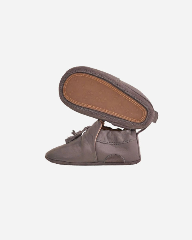 Vue du profil et du dessous des chaussons pour bébé en cuir gris à pompon de la marque Bobine Paris.