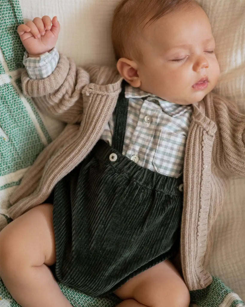 Image d'un bébé portant le cardigan cotelé unisexe à col rond beige clair pour bébé en laine et cachemire de la marque Bobine Paris.