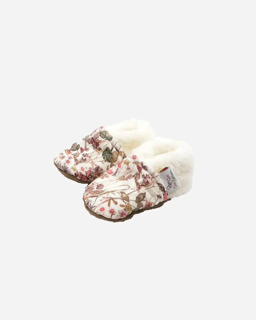 Vue de profil des chaussons pour bébé couleur crème à imprimé fleuri de la marque Bobine Paris.
