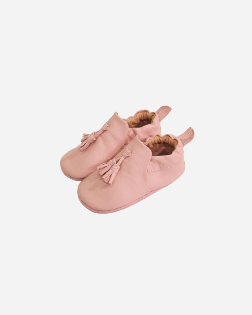 Vue des côtés des chaussons pour bébé fille en cuir rose avec pompon à l'avant de la marque Bobine Paris.