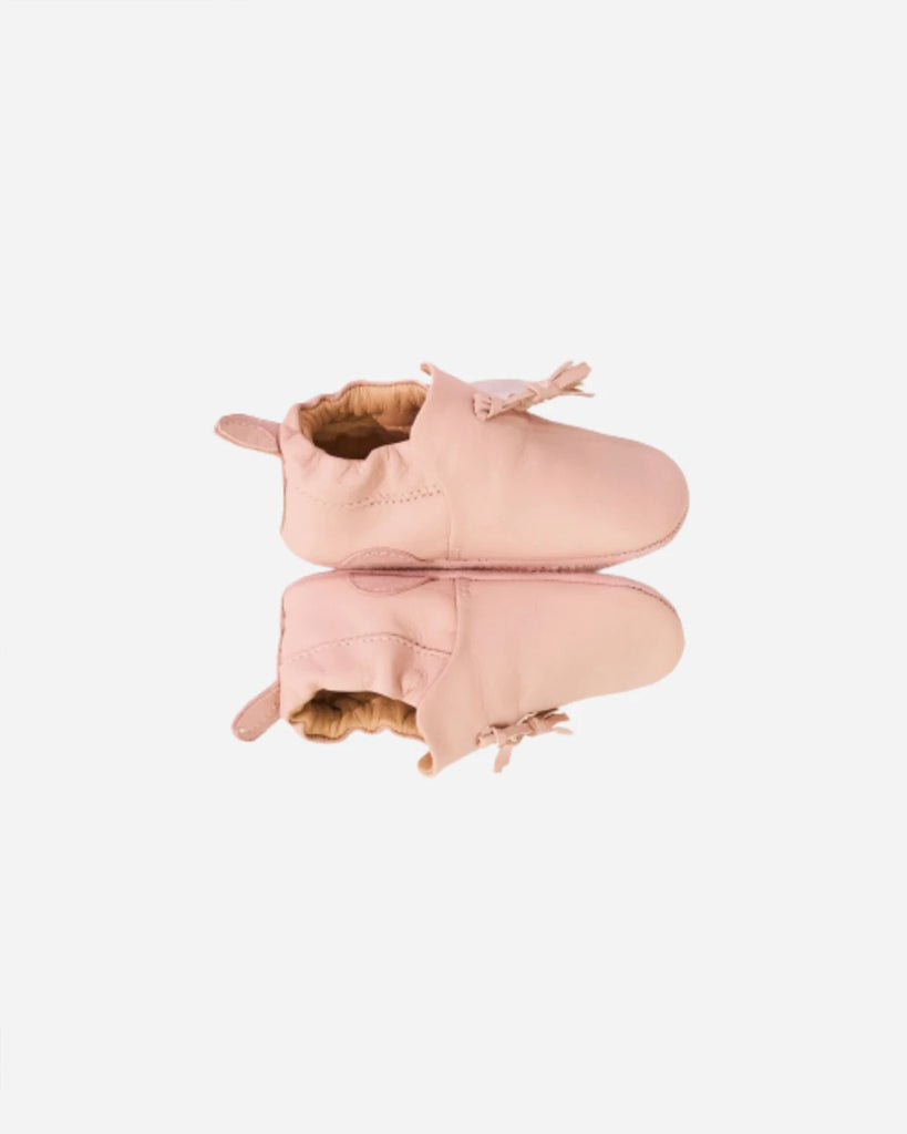 Vue du profil des chaussons pour bébé fille en cuir rose avec pompon à l'avant de la marque Bobine Paris.