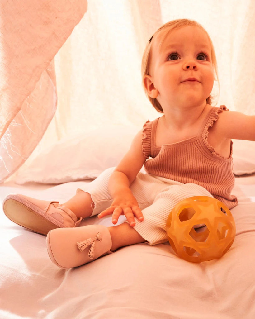 Vue portée des chaussons pour bébé fille en cuir rose avec pompon à l'avant de la marque Bobine Paris.