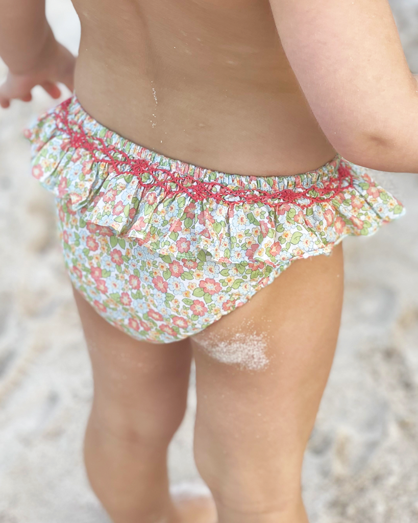 Photo portée de la culotte de bain à froufrous et motifs fleuris prairie verte pour bébé fille de la marque Bobine Paris (vue de dos).