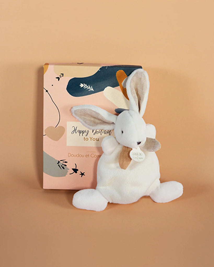 Doudou lapin blanc et beige pour bébé de la marque Bobine Paris avec sa boite sur fond beige.