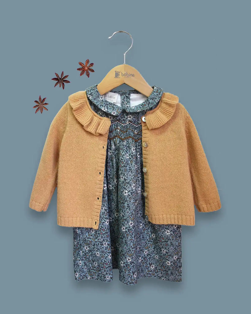 Image d'un look bébé fille composé de la robe en coton Mia smockée fleurs turquoises et du cardigan à col volanté sablé en laine et cachemire Bobine Paris