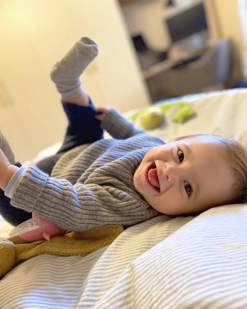 Image d'un bébé garçon portant le pull tricoté en laine et cachemire gris moucheté de la marque Bobine Paris avec un pantalon bleu nuit.