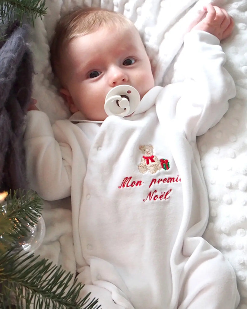 Vue d'un bébé portant un pyjama blanc pour bébé avec broderie ourson et "Mon premier Noel" rouge de la marque Bobine Paris.
