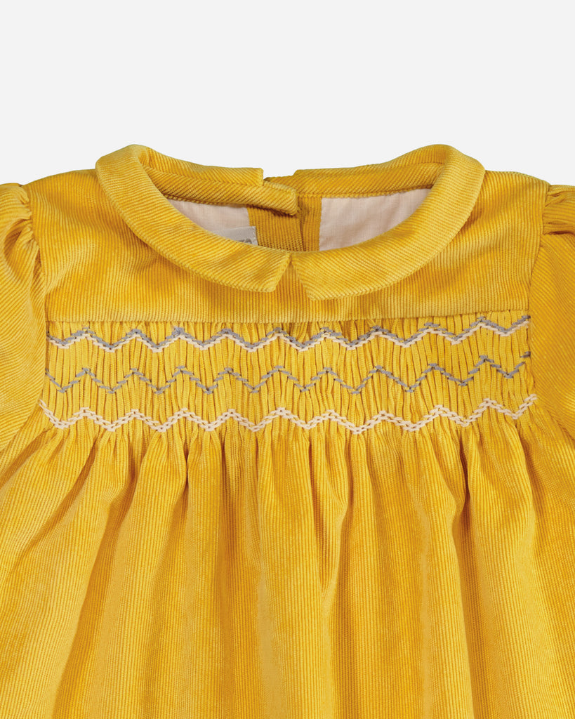 Zoom sur le col claudine d'une robe manches courtes velours jaune moutarde.
