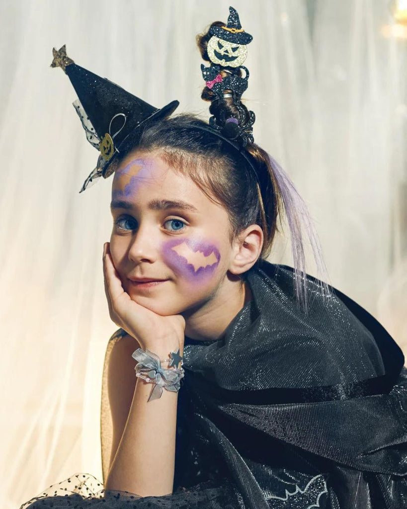 Petite fille portant un serre-tête de de chapeau de sorcière noir avec une citrouille au milieu et une étoile au bout