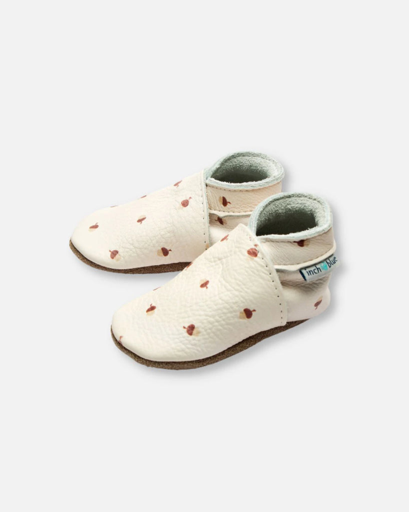Vue de profil des chaussons pour bébé en cuir souple écru à imprimé de la marque Bobine Paris.