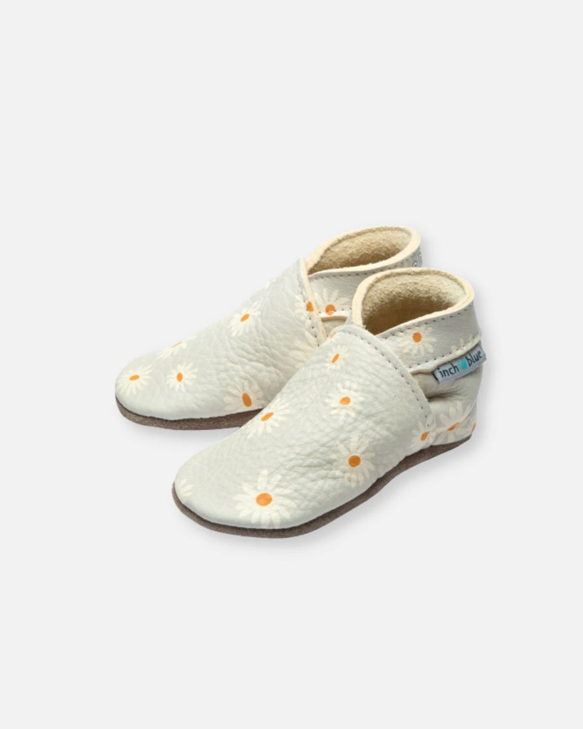 Vue de profil des chaussons pour bébés en cuir couleur perle et ornés de marguerites de la marque Bobine Paris.