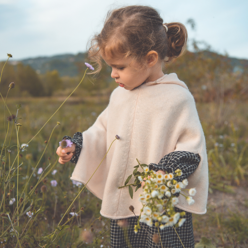 Photo d'une petite fille qui porte le poncho en laine et cachemire rose perle
