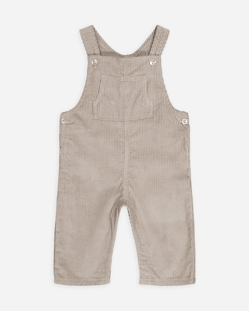 Salopette beige sable velours avec une poche au centre de la poitrine et quatre boutons nacrés.