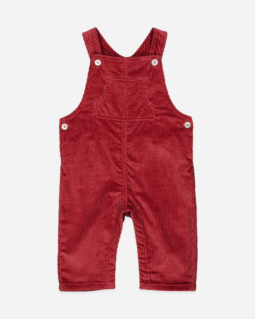 Salopette rouge brique velours avec une poche au centre de la poitrine et quatre boutons nacrés.
