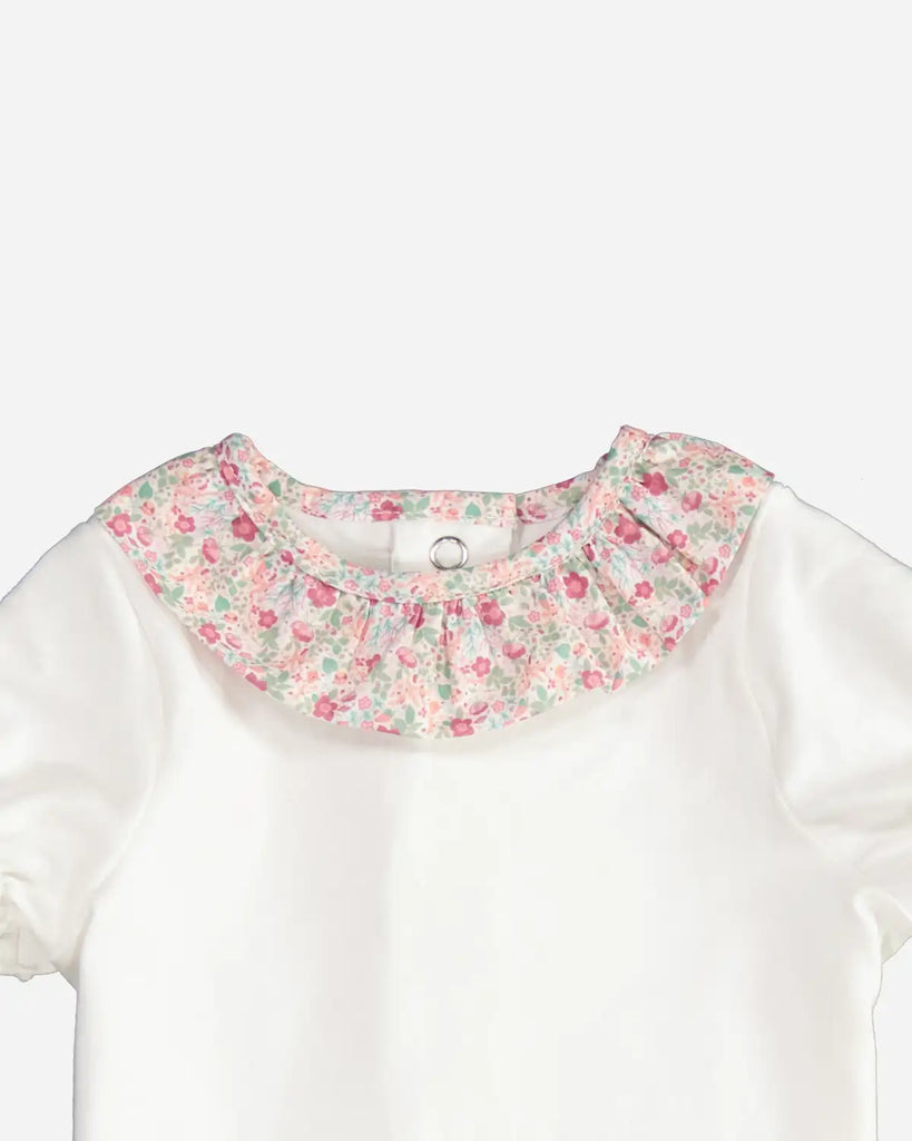 Zoom du body pour bébé fille avec un col volanté à fleurs roses, vertes et oranges de la marque Bobine Paris.
