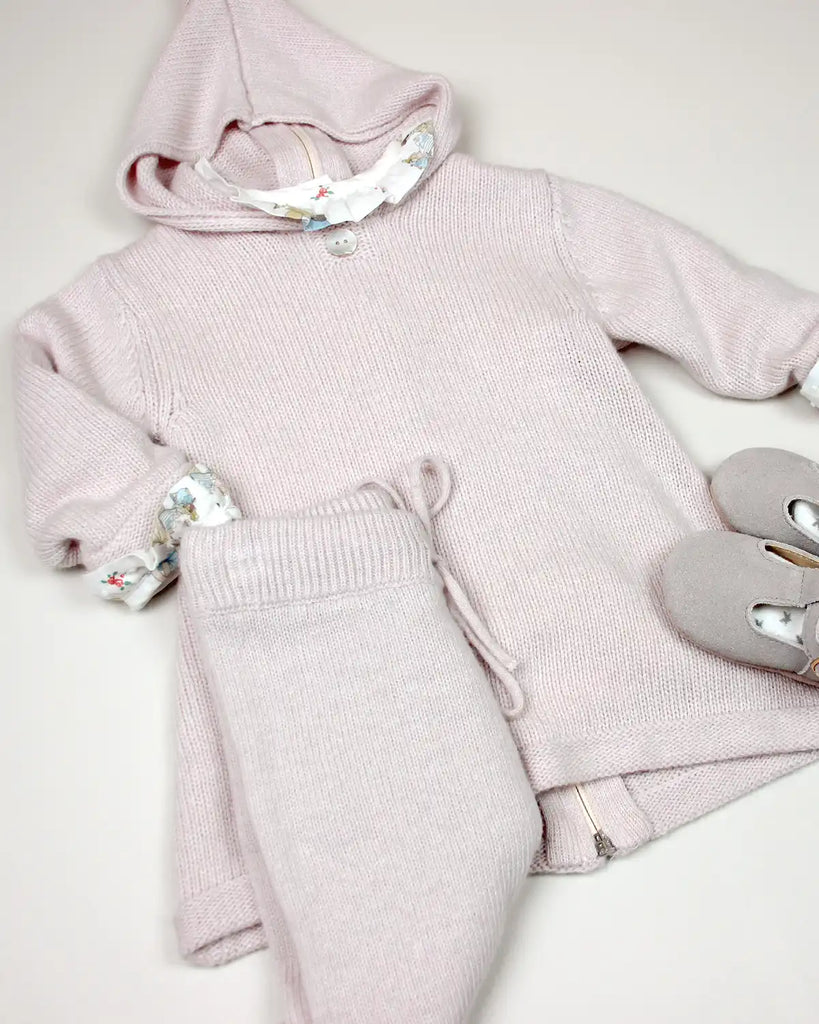 Zoom sur un look avec un burnous bébé en laine et cachemire rose de la marque Bobine Paris et un pantalon assorti..