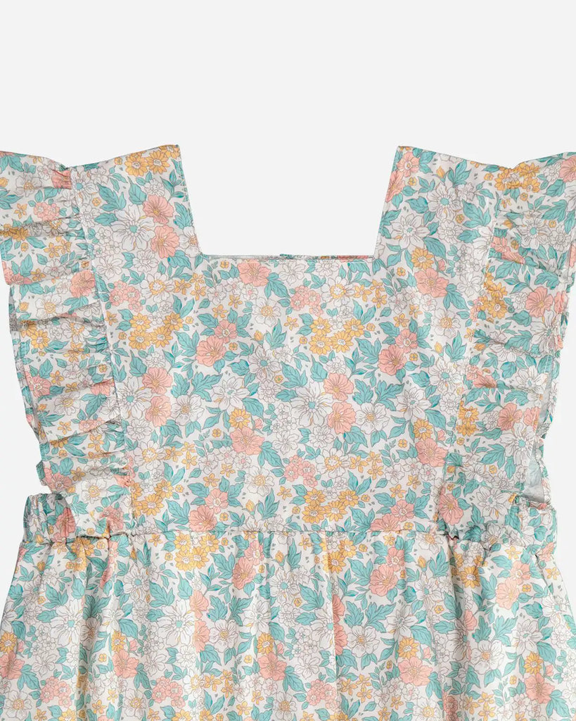 Zoom de la combinaison à motif floral couleur amande et corail et à détails volantés sur les bretelles pour bébé fille de la marque Bobine Paris.