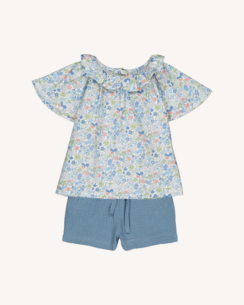 Look pour bébé composé d'une blouse fleurie bleue à col volanté et d'un short en gaze de coton de la marque Bobine Paris.
