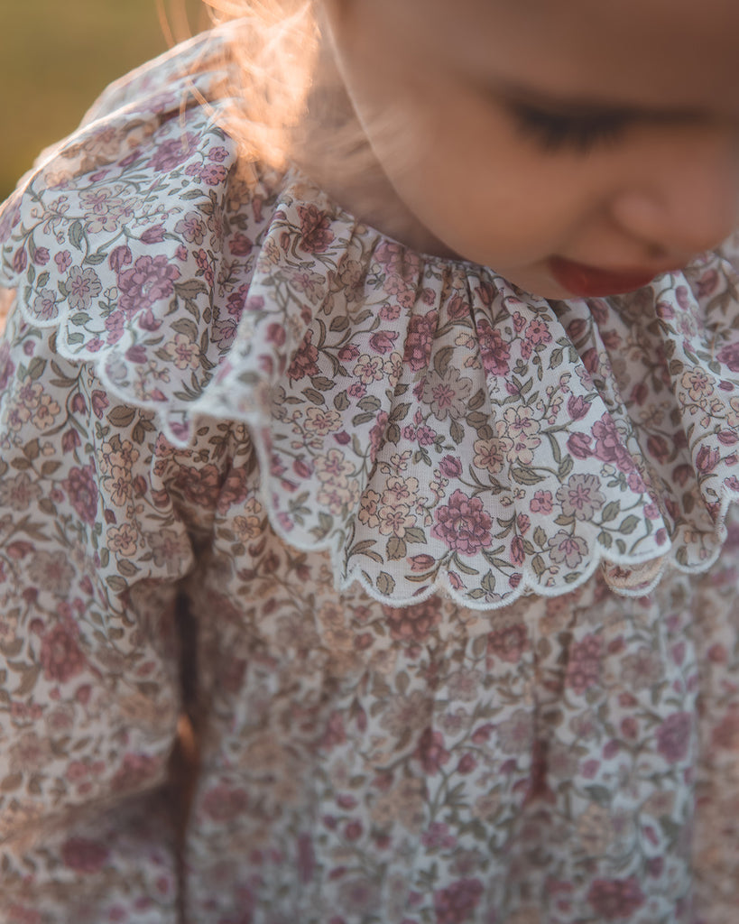 Zoom au col d'une blouse à imprimés mauves.