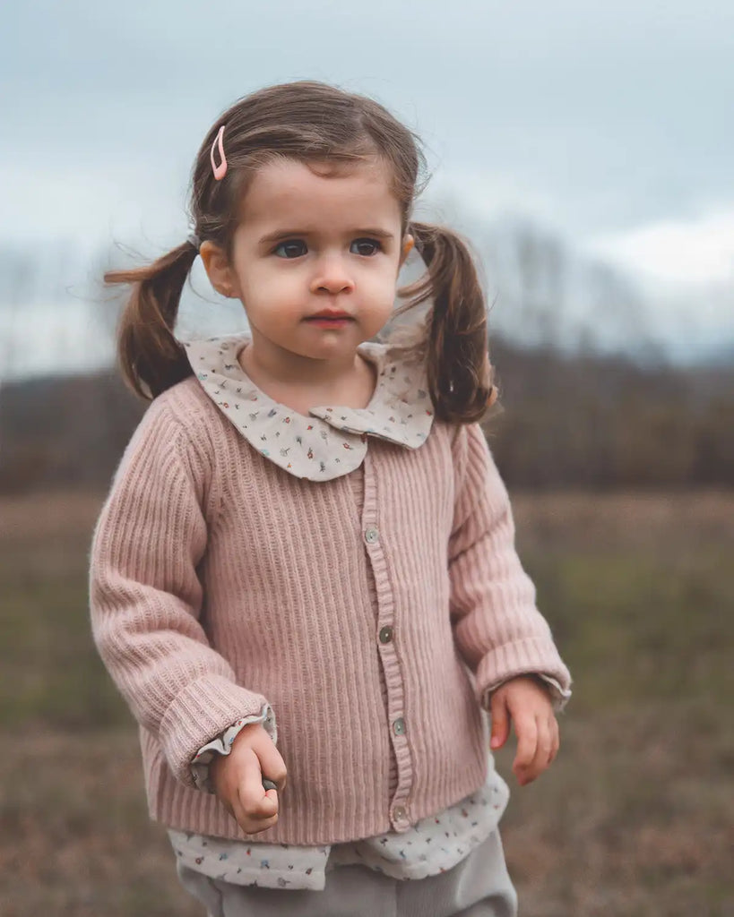 image d'une petite fille portant le cardigan à col rond côtes bébé de couleur rose poudre en laine et cachemire Bobine Paris