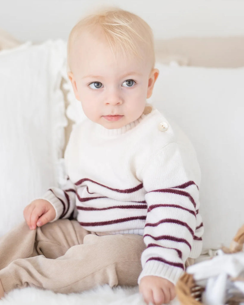 Image d'un petit garçon portant le pull bébé écru à rayures bordeaux de la marque Bobine Paris