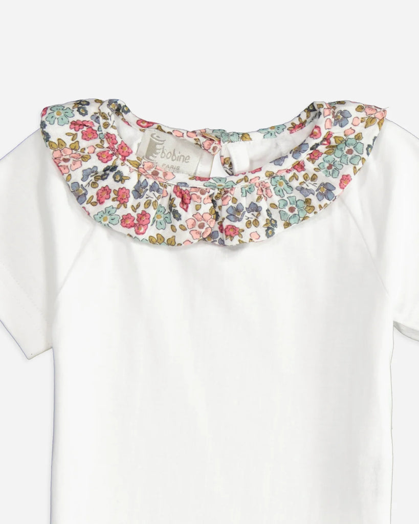 Zoom du t-shirt pour bébé fille à manches courtes avec un col volanté à fleurs bleues et roses de la marque Bobine Paris.