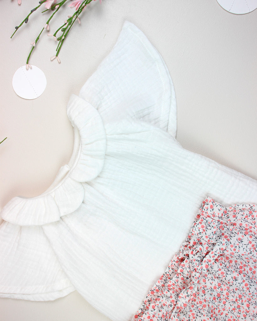 Zoom sur le look pour bébé composé d'une blouse en gaze de coton blanc et d'un panty fleuri de la marque Bobine Paris.