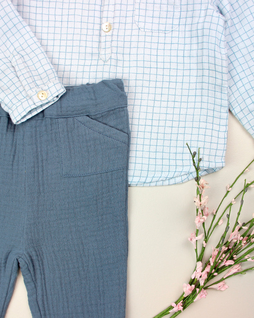 Zoom sur le look composé du pantalon en gaze de coton jean clair pour bébé et d'une chemise quadrillée bleue de la marque Bobine Paris.