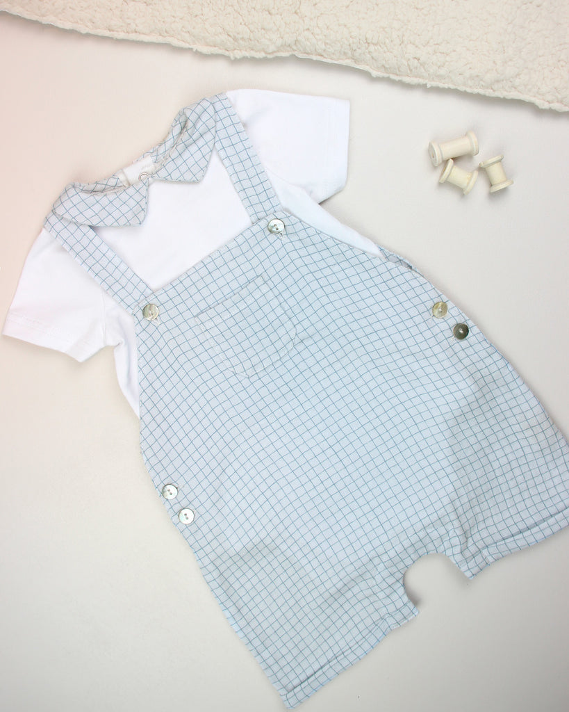 Look constitué d'une salopette pour bébé garçon à motif quadrillé bleu et d'un t-shirt blanc avec col point assorti de la marque Bobine Paris (vu sous un autre angle).